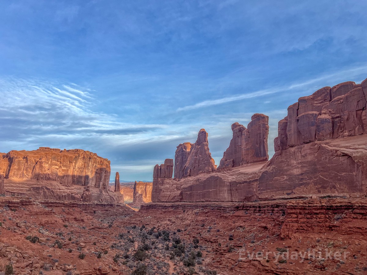 Looking down the thoroughfare of Park Avenue, with a row of towering pillars on the right of the valley and a large block on the left.  The trail descends through the center of the wash.