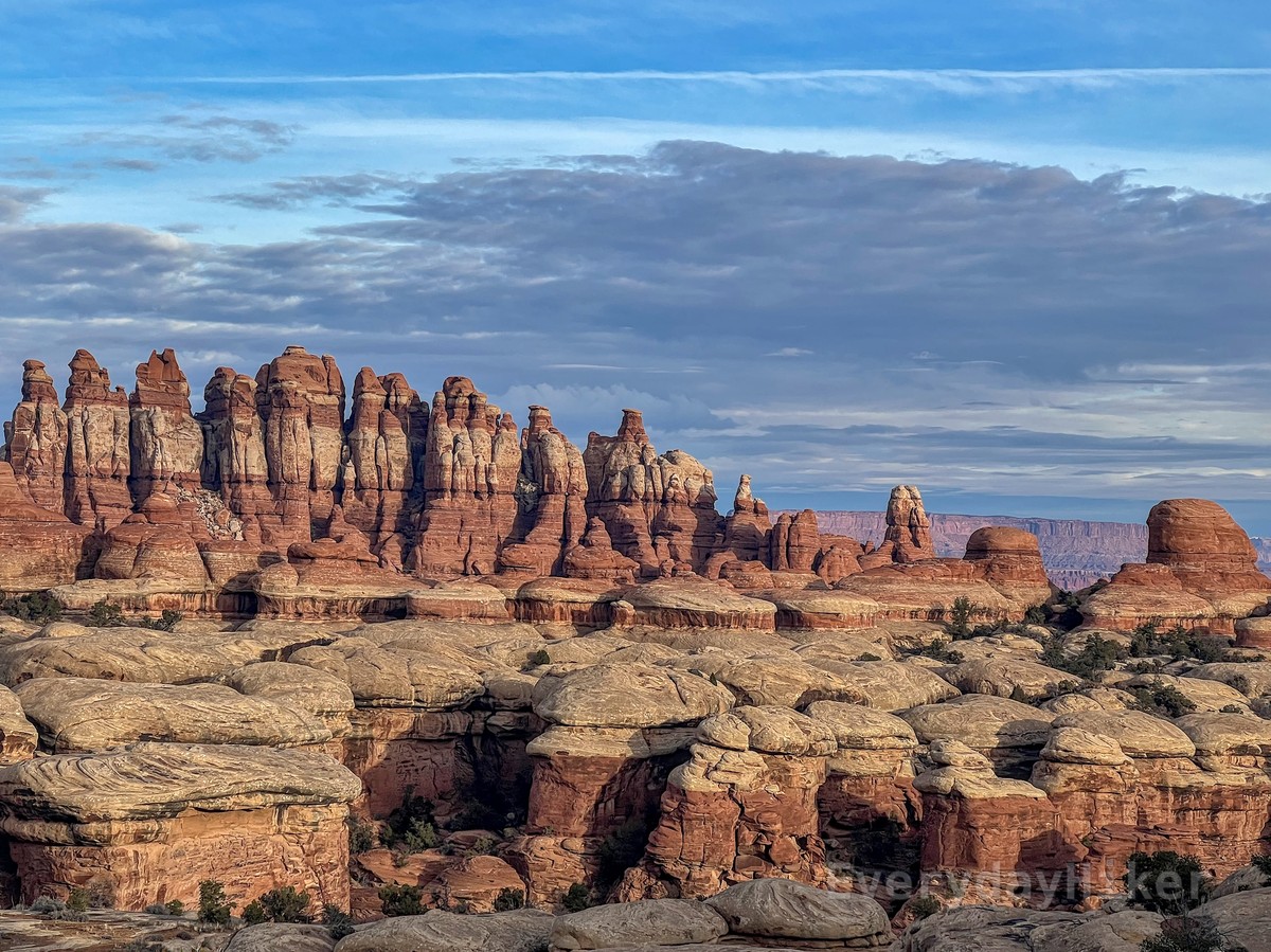 A collection of sandstone 'needles' rising up towards the morning sky. Layers of red and white sedimentary rock may be seen among them.  In the lower frame, some more eroded pillars make up the valley floor.