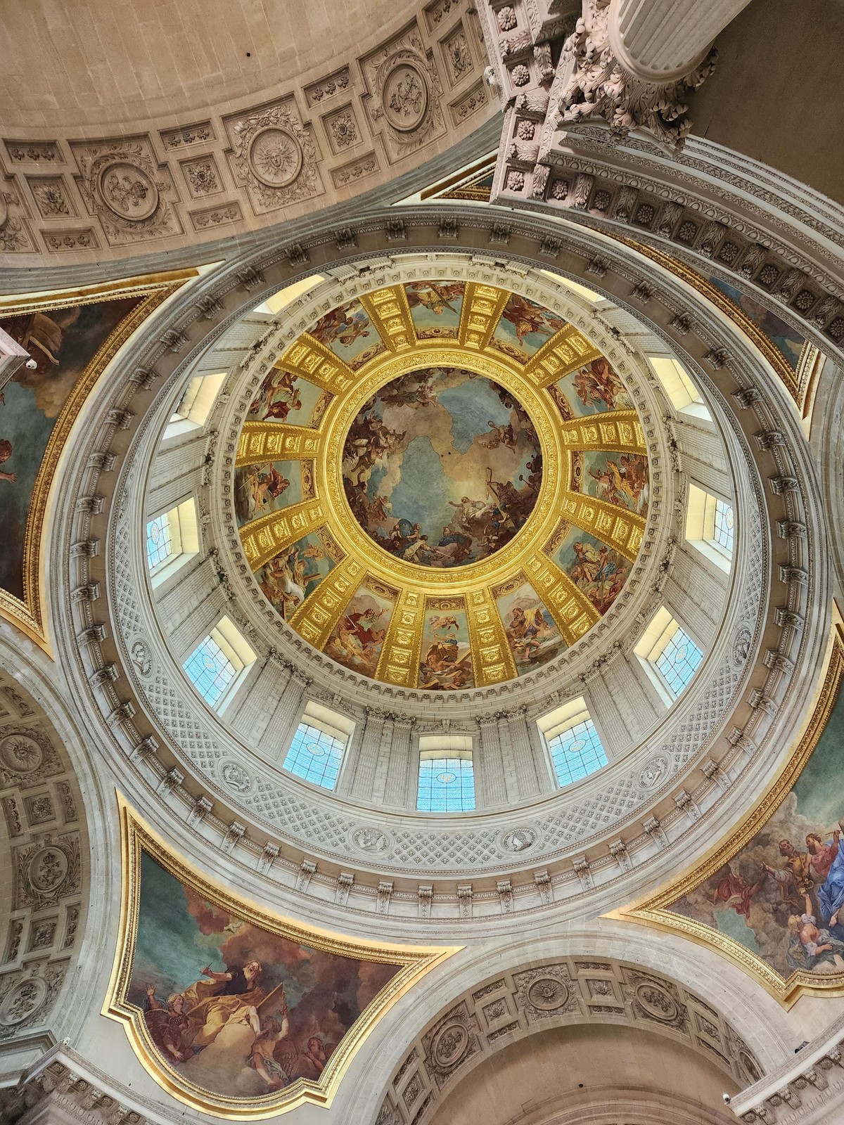 "looking up at the large dome, with frescoes and arches below the base and 12 windows encircling the dome\u0027s bottom level. above each window is a fresco of a biblical scene, and the center of the dome is a large circular fresco"